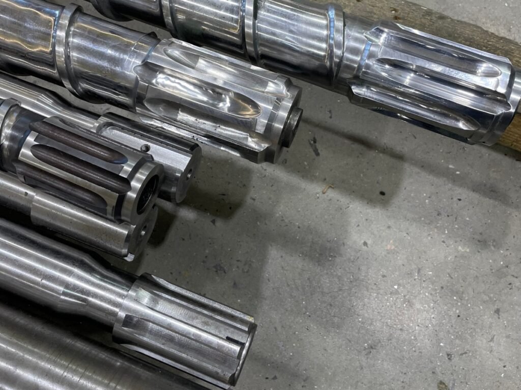 Close-up of metal extruder screws and machined shaft ends
