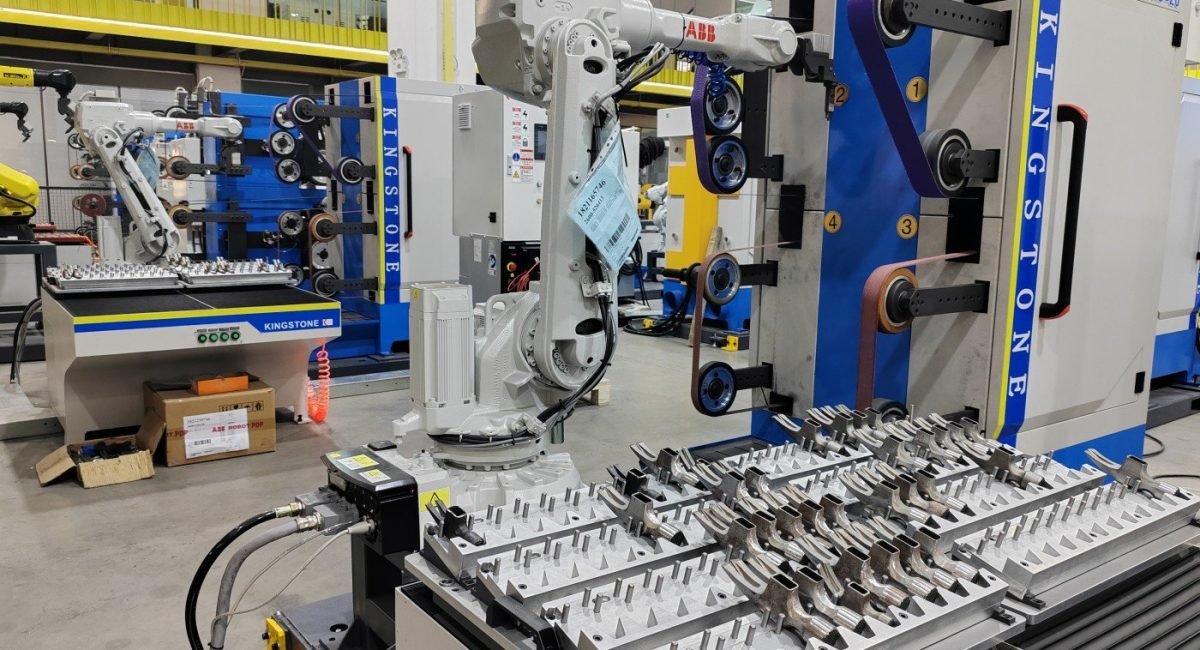 Robotic grinding workstation with metal workpieces ready for processing